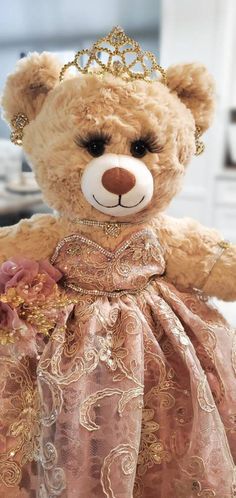 a brown teddy bear wearing a pink dress with a tiara on it's head