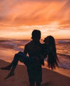 a man carrying a woman on his back while standing in the sand near the ocean