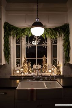 a kitchen decorated for christmas with lights and garland on the window sill, sink and windowsill