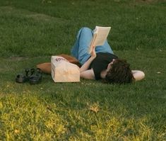 a person laying on the grass reading a book