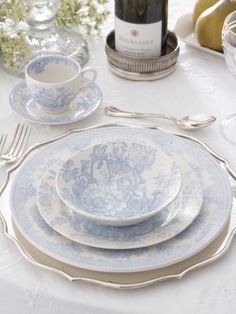 a table set with plates, silverware and wine bottle