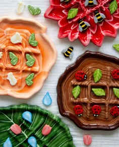 three ceramic plates with designs on them sitting on a table next to leaves and flowers