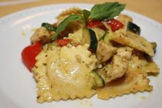 a white plate topped with pasta and veggies on top of a wooden table