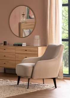 a living room with a chair, dresser and large mirror on the wall above it