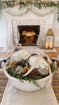 a bowl filled with silver ornaments on top of a table next to a fire place