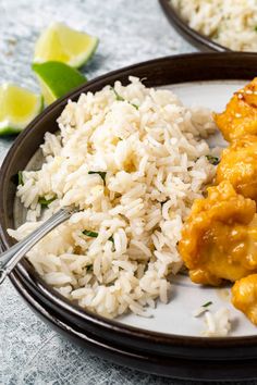 two plates filled with rice and chicken next to lime wedges on the counter top