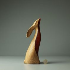 a wooden sculpture sitting on top of a table next to a gold coin in front of it