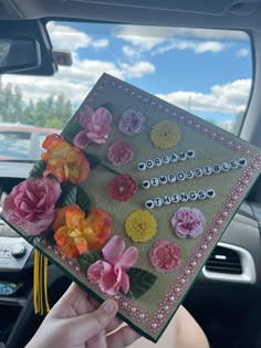 someone is holding up a card with flowers on it in the back of a car