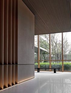 an empty room with large windows and wooden slats on the wall, along with benches