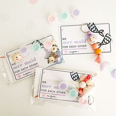 two bags filled with buttons on top of a white table next to confetti