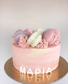 there is a pink cake with macaroons on it and the words made out of frosting