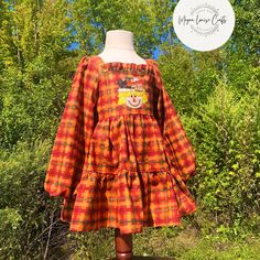 an orange and yellow plaid dress on a mannequin head with trees in the background