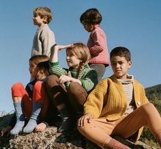 four children sitting on top of a rock