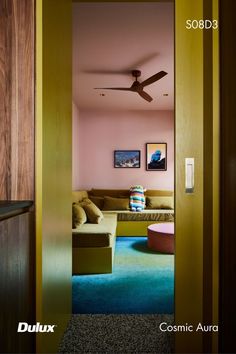 an open door leading to a living room with pink walls and green carpeted flooring