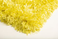 a yellow shaggy rug on a white surface