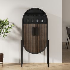 a black and brown cabinet sitting on top of a wooden floor next to a potted plant