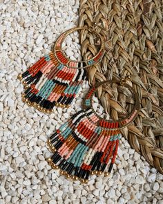 a pair of earrings sitting on top of a pile of rocks next to a basket