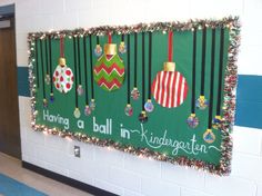 a bulletin board decorated with christmas ornaments and writing on the wall in a school hallway