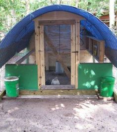 an outdoor chicken coop with two buckets on the floor and one in the corner