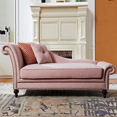 a pink chaise lounge sitting on top of a rug in front of a fireplace