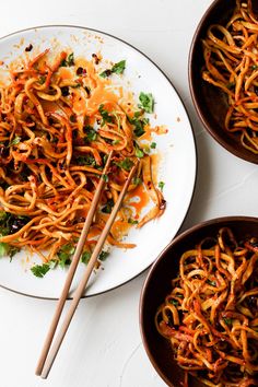 two plates with noodles and chopsticks on them