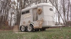 an rv parked in the grass with chairs around it and a bow on the door