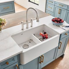 a kitchen with blue cabinets and white counter tops, two sinks in front of an island