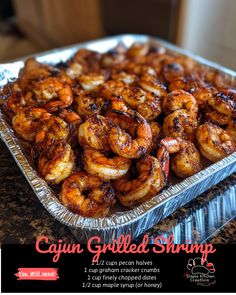 there is a tray of cooked shrimp in foil on the kitchen counter with text overlay that reads cajun grilled shrimp