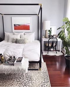 a white bed sitting in a bedroom on top of a hard wood floor