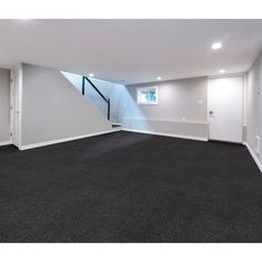 an empty room with black carpet and white walls