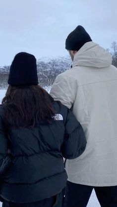 two people standing in the snow looking at something