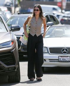 a woman is walking down the street with her hand in her pocket and wearing sunglasses