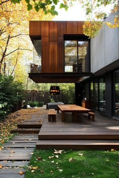 a modern house with wooden decking and large windows in the back yard, surrounded by trees