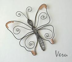 a wire butterfly sculpture sitting on top of a white surface with the word venus written below it