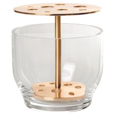 a glass cup with a metal stand on it's side and four holes in the middle