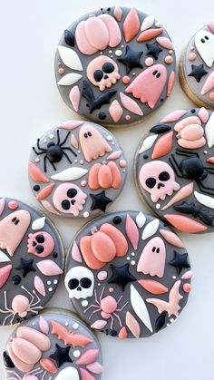 some decorated cookies are sitting on a table with black and pink frosted icing