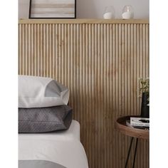 a bed with white sheets and pillows next to a wooden paneled wall in a bedroom