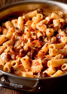 a pan filled with pasta and sauce on top of a wooden table