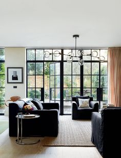 a living room filled with black furniture and lots of windows