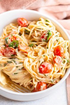 a white bowl filled with pasta and tomatoes