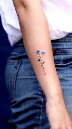 a small blue flower tattoo on the wrist