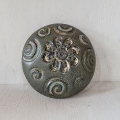 a decorative metal object sitting on top of a wooden table next to a white wall