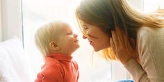 a woman is holding a baby in her lap and looking at the child's face