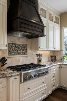 a stove top oven sitting inside of a kitchen next to white cabinets and counter tops