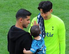 two men and a young boy standing on a soccer field