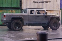 a gray truck is parked in front of some shipping containers