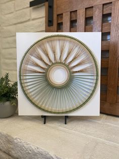 a white card with a circular design on the front and bottom, sitting next to a potted plant