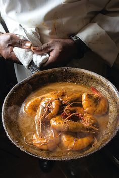 a man holding a pan filled with cooked shrimp