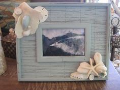 there is a picture frame on the table with shells and seashells around it