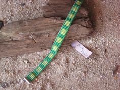 a green and yellow lanyard with a tag attached to it sitting on the ground